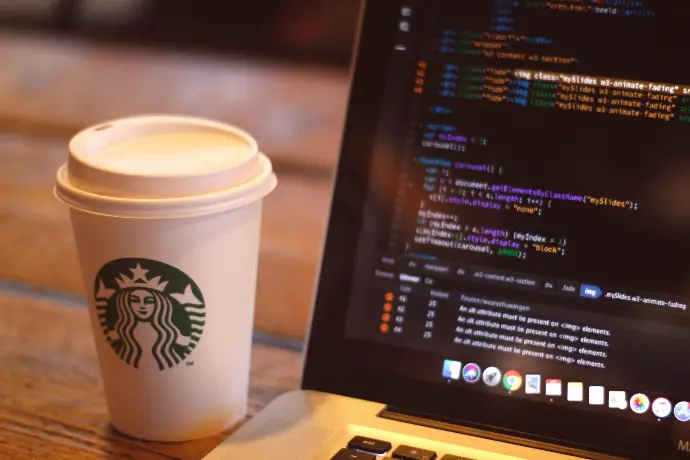 white starbucks cup beside black and silver laptop computer